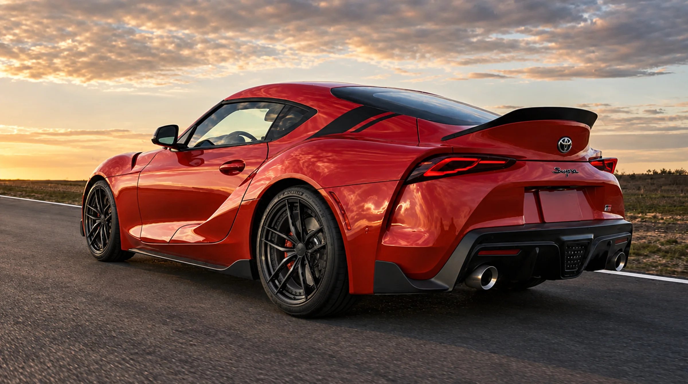 Red Toyota Supra driving on the road